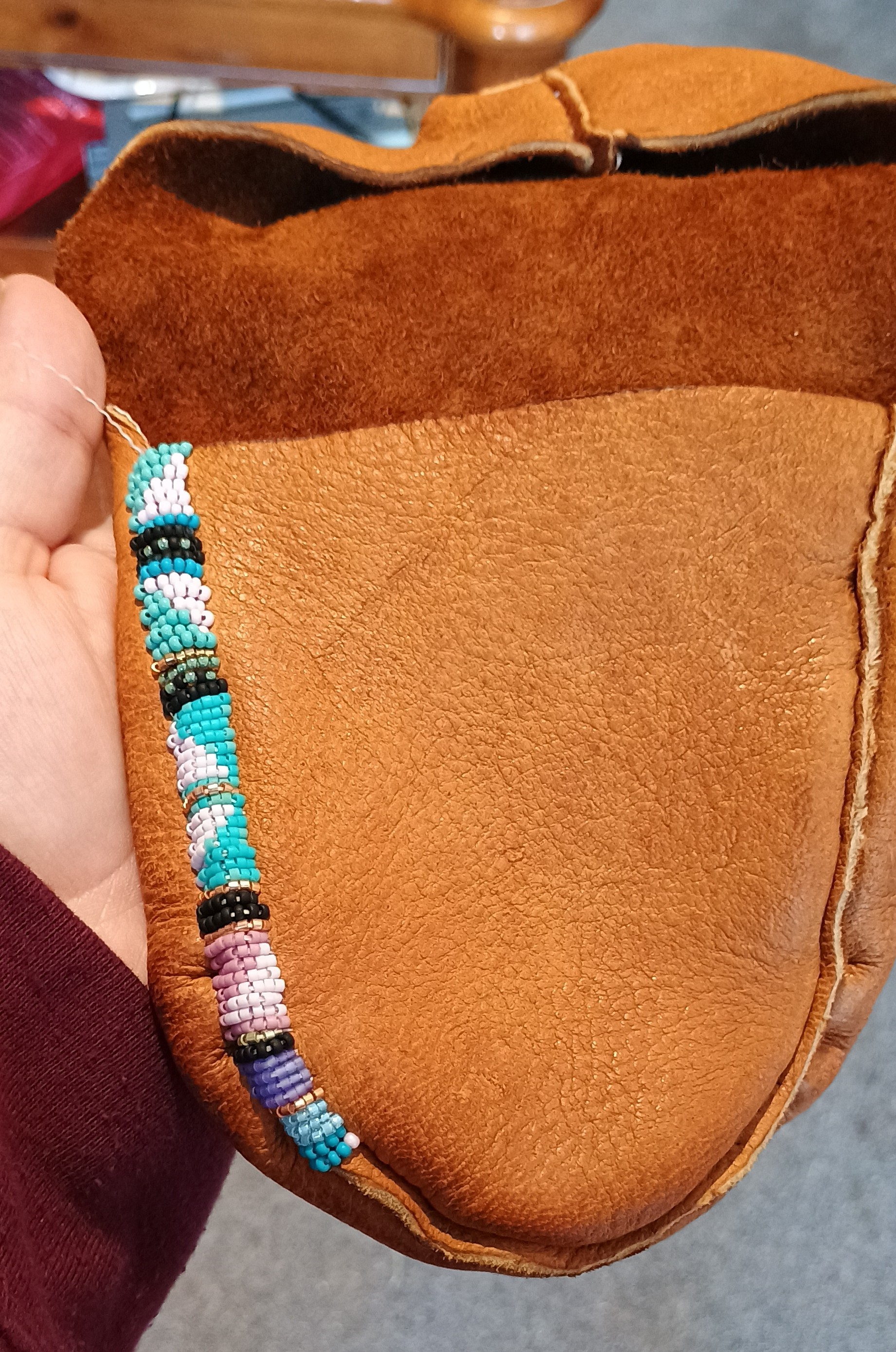 partially sewn, brown moccasin with a beaded rim in progress