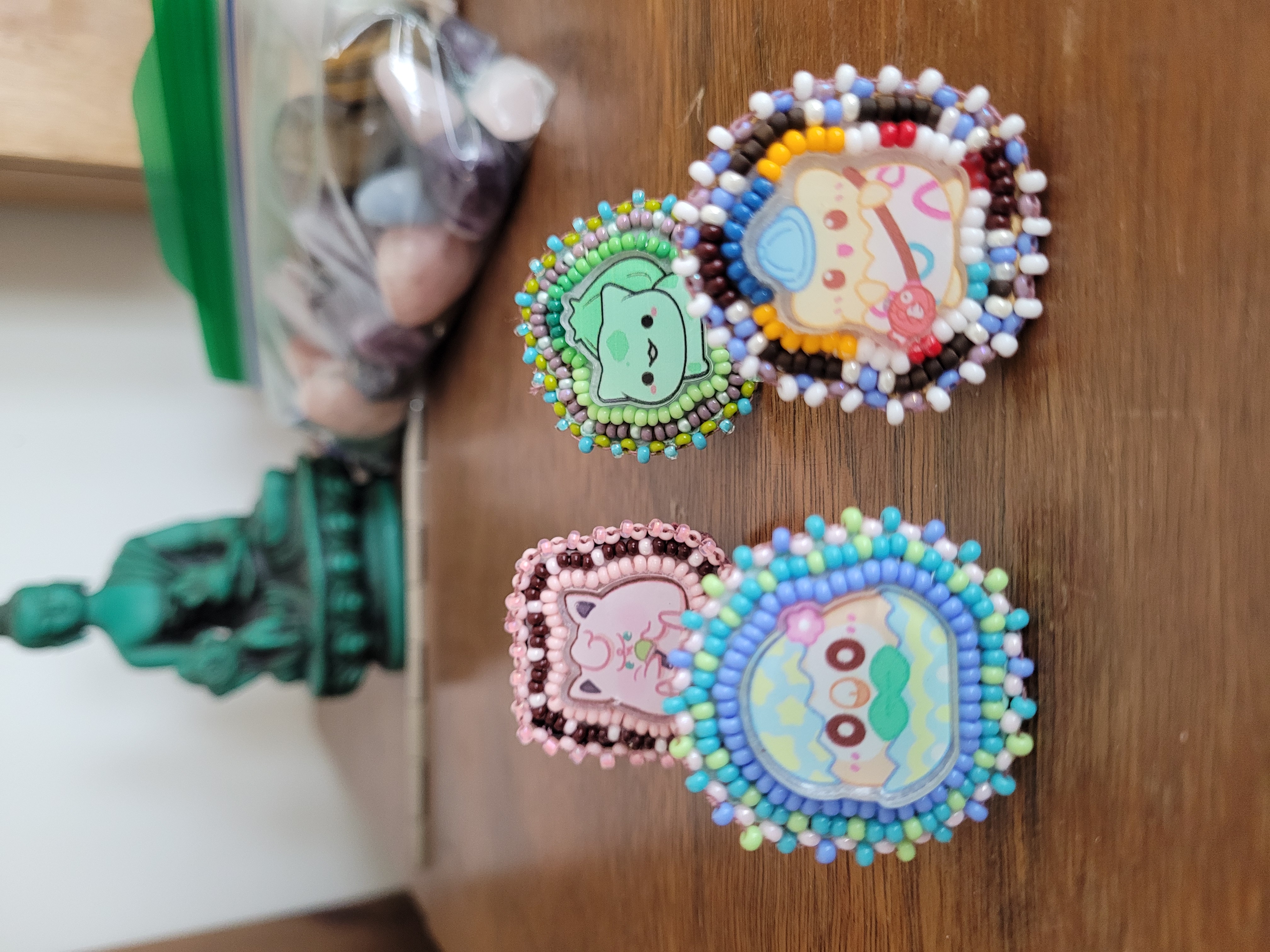 four different beaded pokemon studes; from left to right, top to bottom: Jigglypuff, Bulbasaur, Rowlet, and Togepi